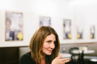 Regisseurin Jessica Bollag in einer Interviewsituation. Sie hebt die Hand und blickt konzentriert zu ihrer Interviewerein, die jedoch nicht im Bild ist.
