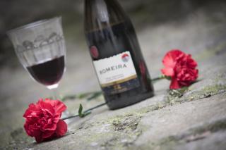 Foto von zwei roten Nelken und einer Flasche und einem Glas Portwein
